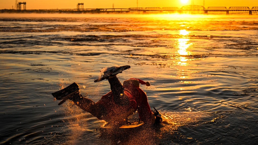 সান্তা স্যুটে মন্ট্রিল বডি সার্ফার -14 ডিগ্রি আবহাওয়ায় নদীতে আঘাত করেছে৷